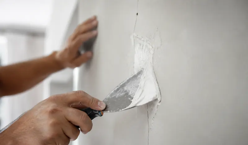 Scheur in een muur wordt vakkundig hersteld met plamuur