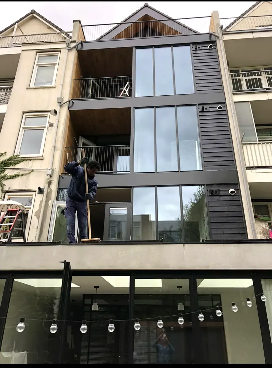 Vernieuwde gevel met grote kozijnen en donkere gevelbekleding