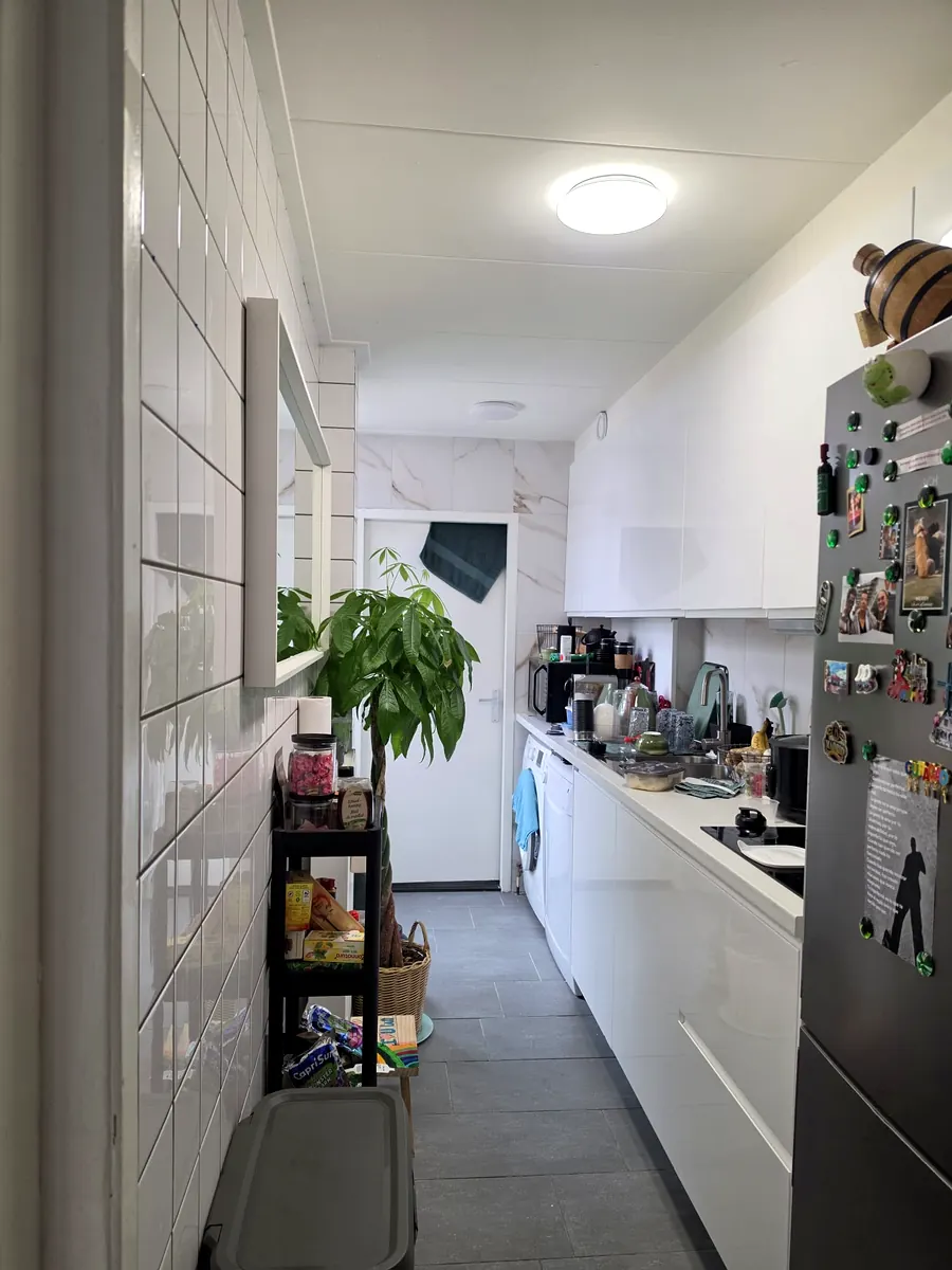 De nieuwe keuken in gebruik: strakke witte fronten, marmerlook wand en alles op zijn plek